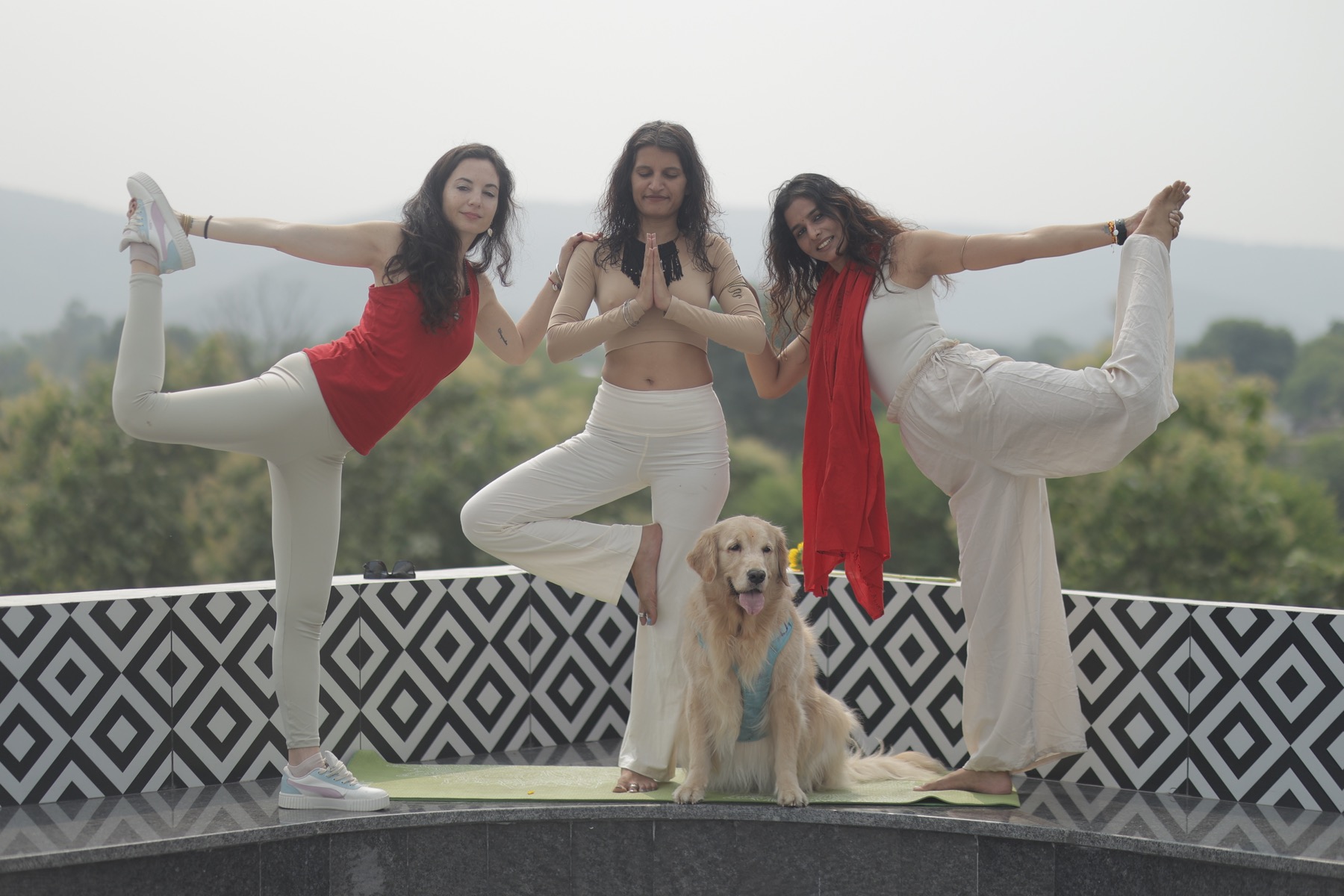 Three retreat participants sharing yoga poses with a golden retriever in Ranthambore